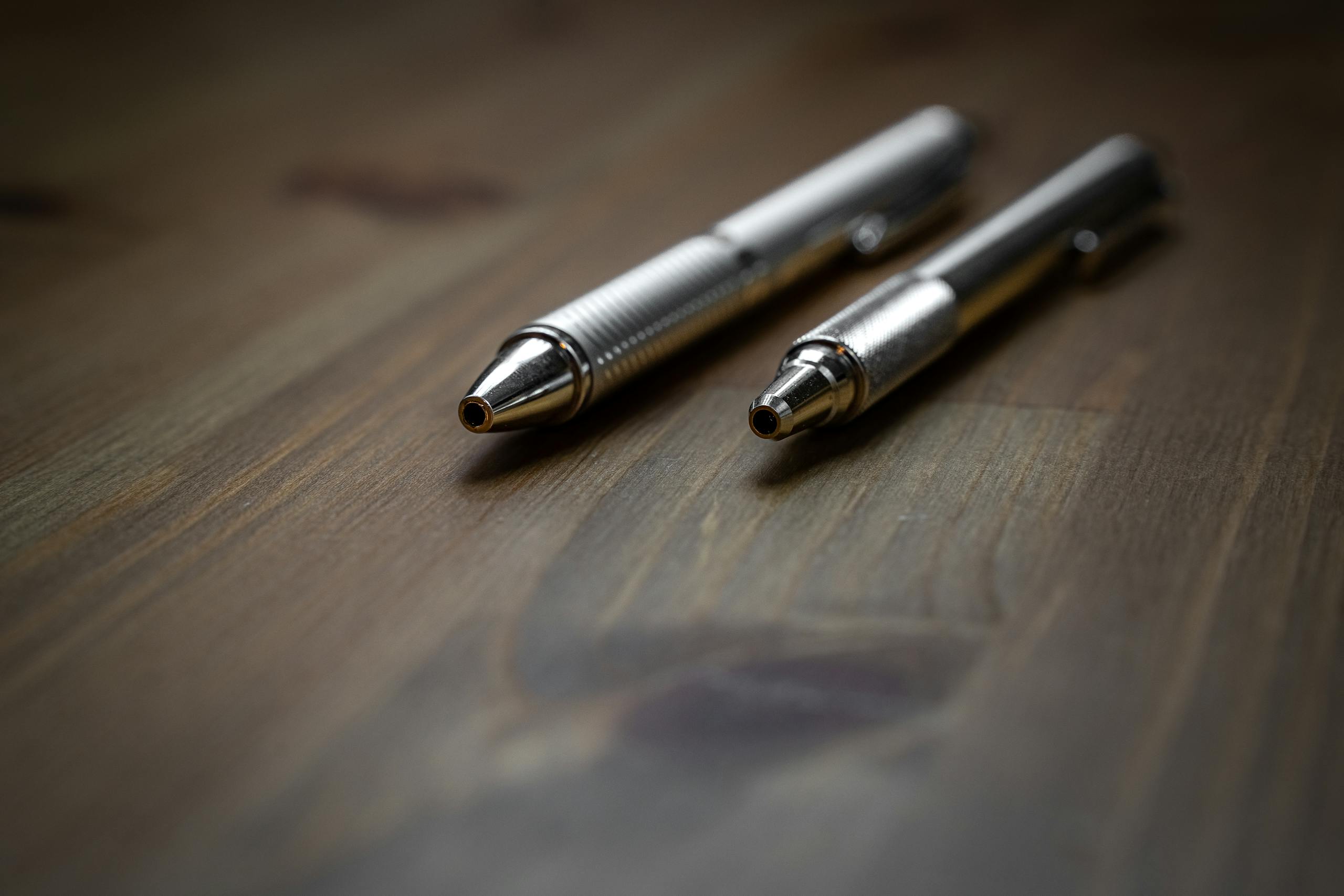 Close-up view of two silver ballpoint pens placed on a wooden surface, ideal for business themes.